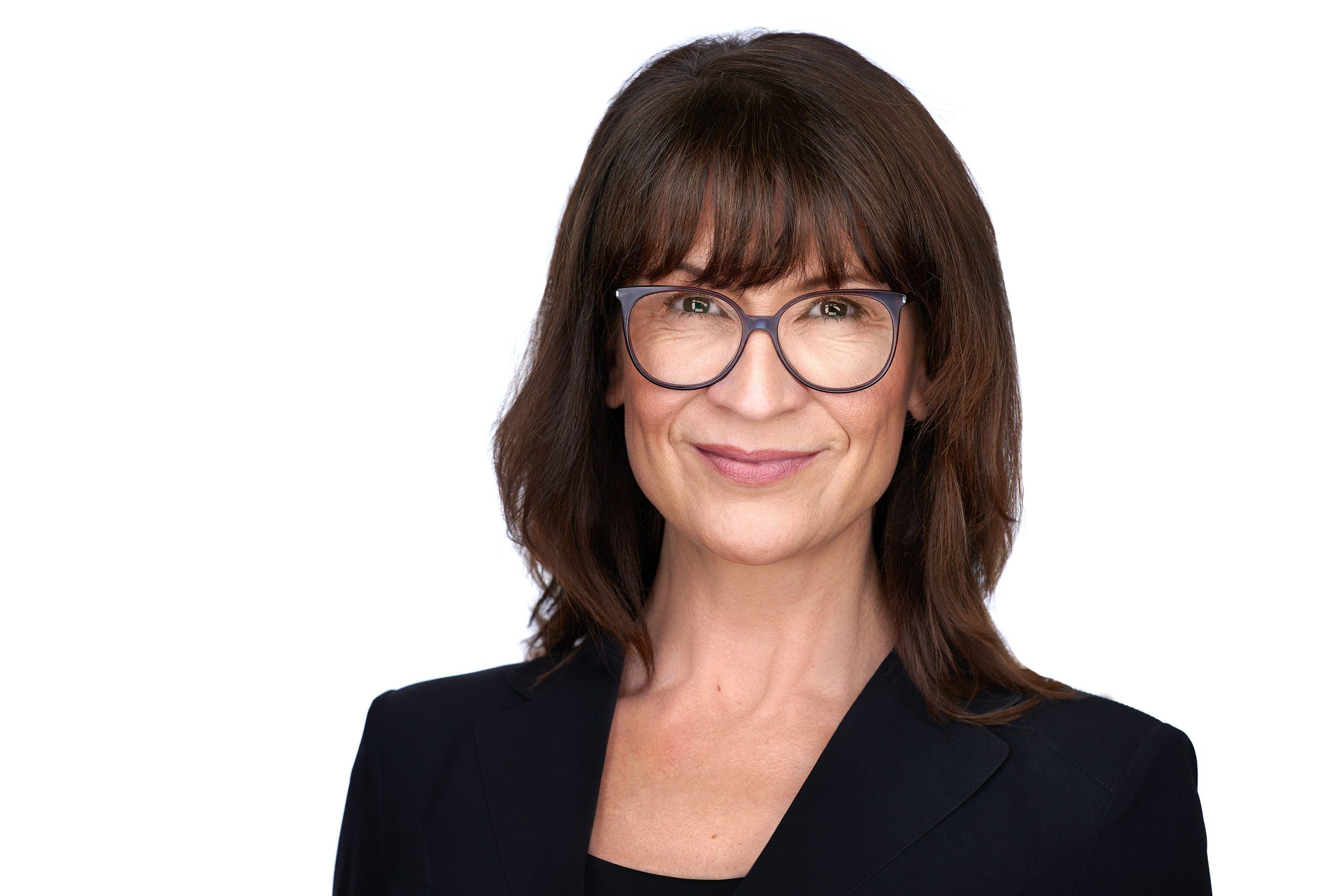 Businessportrait einer Frau mit Brille und dunklen Haaren im schwarzen Blazer vor weißem Hintergrund, fotografiert im Studio in Köln