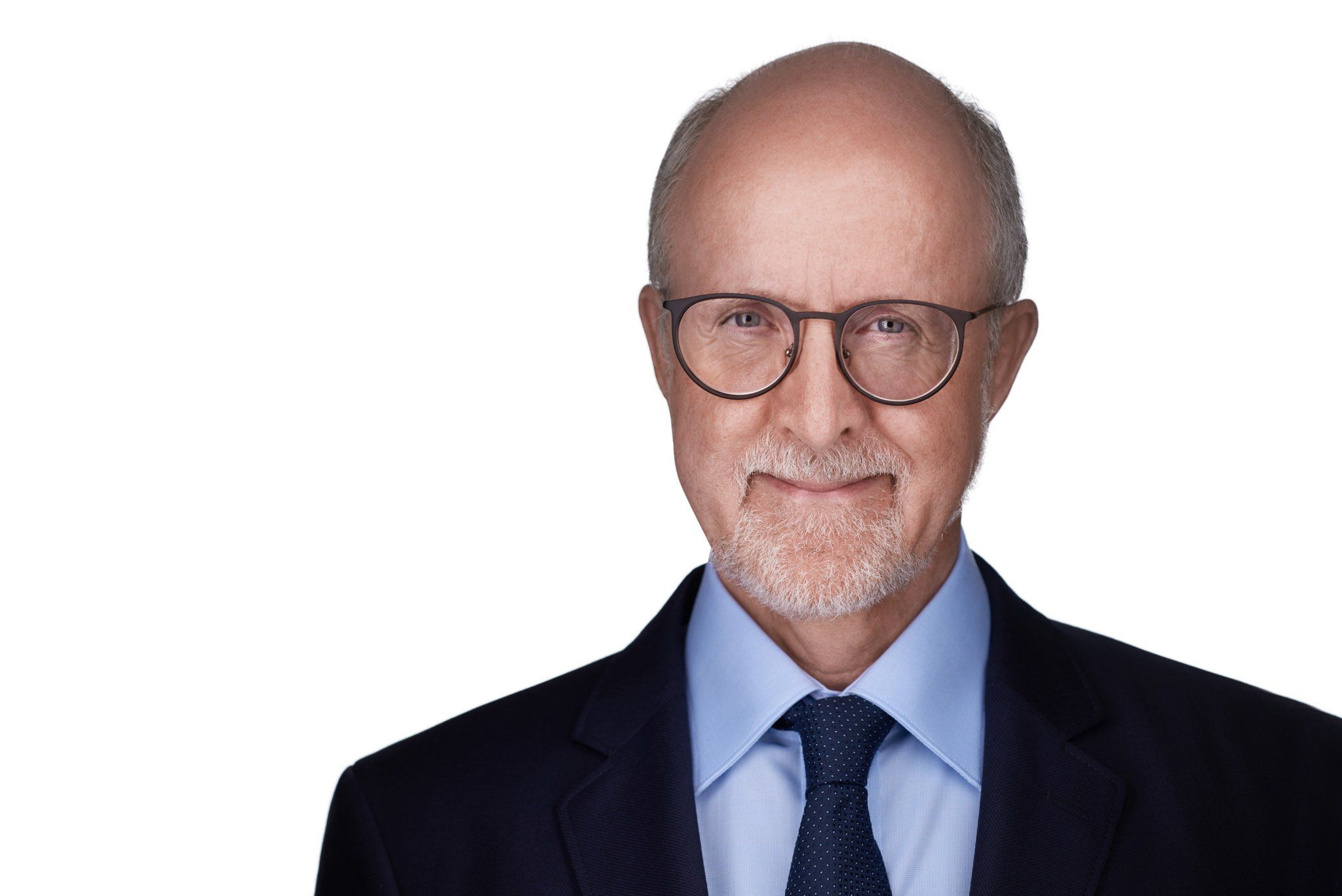 Headshot eines älteren Mannes mit Brille und grauem Bart im dunklen Anzug mit Krawatte vor weißem Hintergrund, fotografiert im Studio in Köln