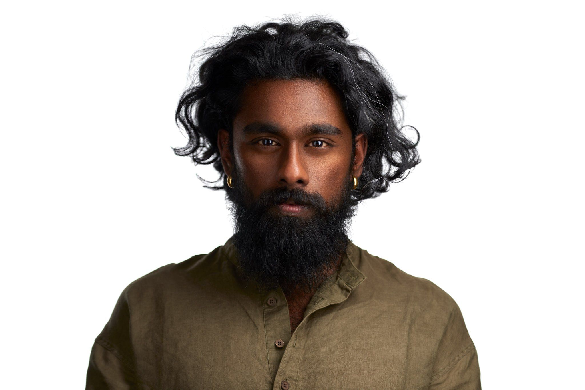 Headshot eines Mannes mit langen Locken und Vollbart im olivgrünen Hemd vor weißem Hintergrund, fotografiert im Studio in Köln